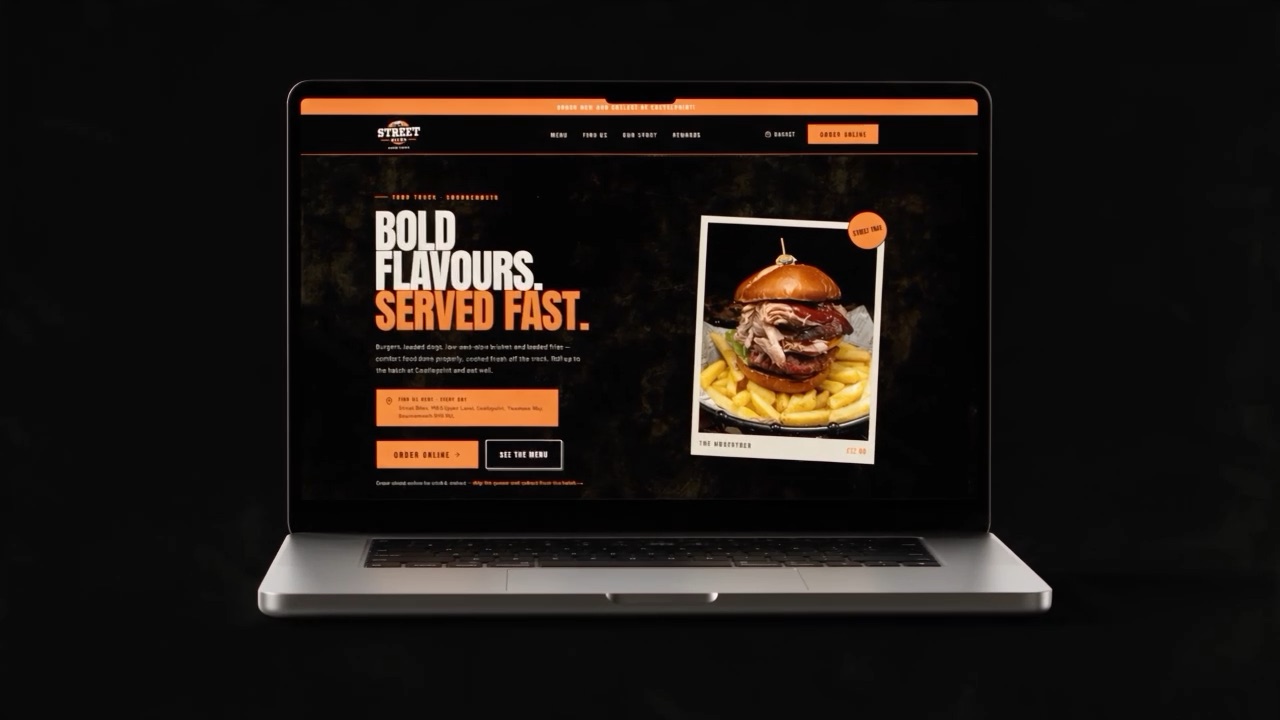 The Street Bites homepage square on to camera: hero headline, address panel, two calls to action and a photograph of a loaded burger and fries priced at twelve pounds.