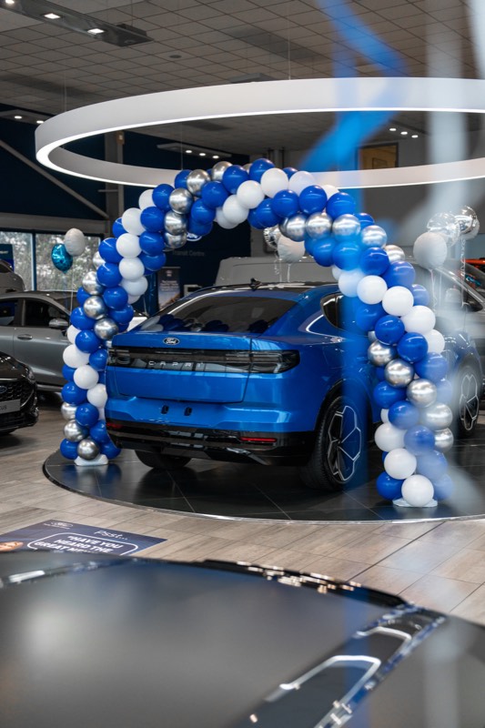 All-electric Ford Capri on a showroom turntable under a balloon arch at a Foray Motor Group launch event